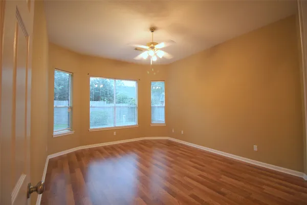 a view of an empty room with window and chandelier fan