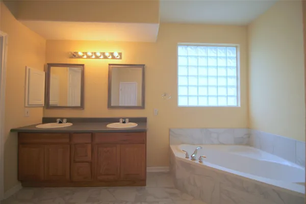 a bathroom with a tub a sink and mirror