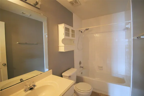 a bathroom with a bathtub shower sink vanity and toilet