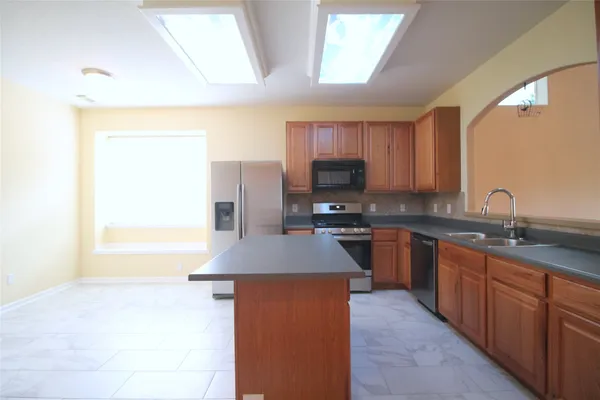 a kitchen with kitchen island granite countertop a sink appliances cabinets and a counter top space