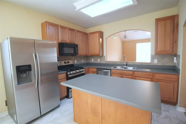 a kitchen with stainless steel appliances granite countertop a refrigerator a sink a stove a microwave and island