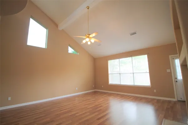 an empty room with wooden floor and windows