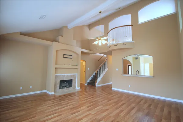 a view of an empty room with wooden floor fireplace and a window