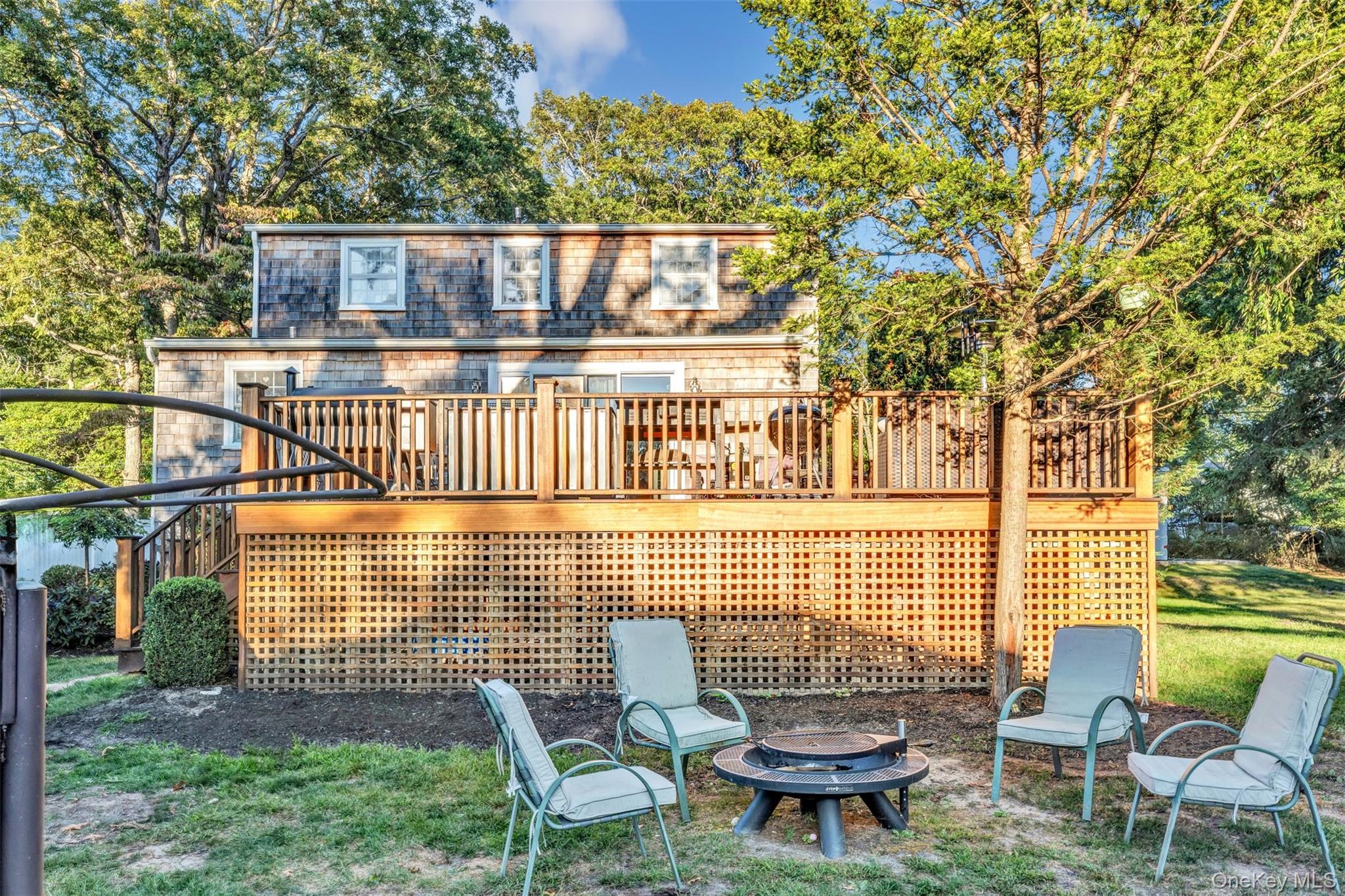 81 Beach Road Wading River, NY 11792 - Photo 11 of 25 Rear view of house featuring stairway, a deck, an outdoor fire pit, view of wooded area, and a yard