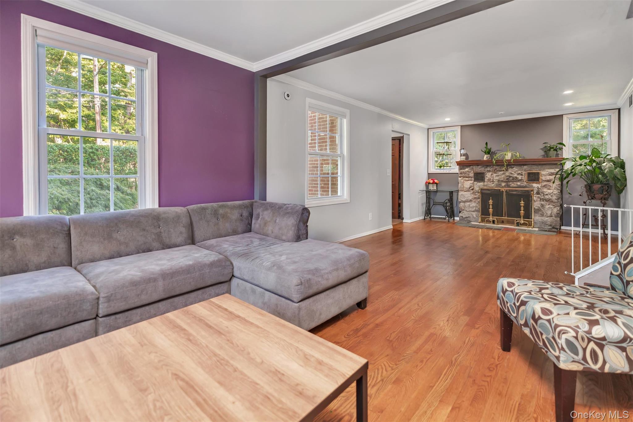 81 Beach Road Wading River, NY 11792 - Photo 5 of 25 Living room with wood finished floors, crown molding, and a stone fireplace