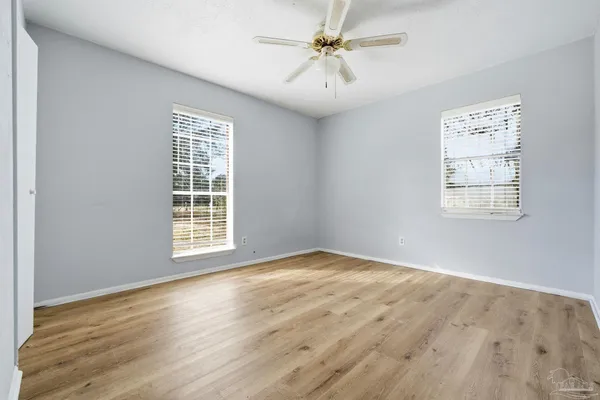 a view of an empty room with a window and wooden floor