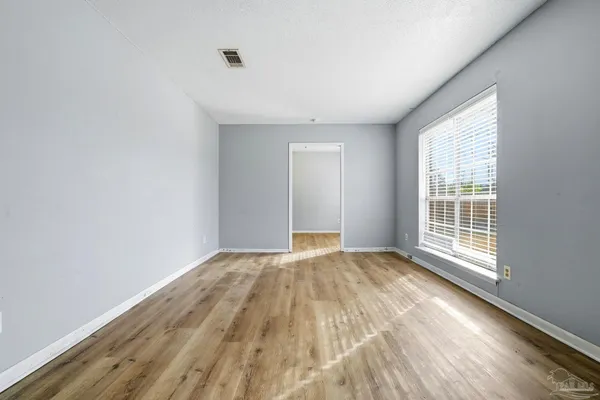 a view of an empty room with wooden floor and a window