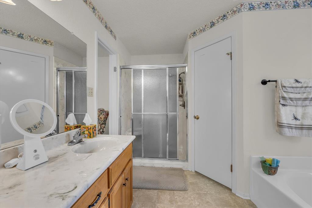 107 Fort Graham Circle Waco, TX 76705 - Photo 16 of 40 Full bathroom with a shower stall, vanity, a garden tub, and a textured ceiling