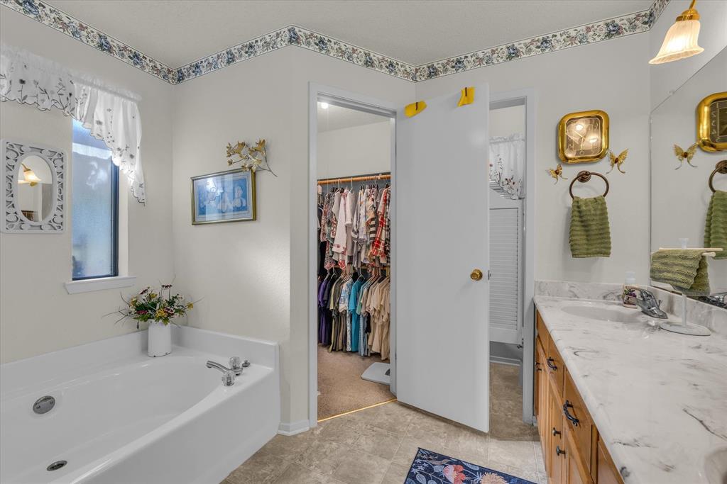 107 Fort Graham Circle Waco, TX 76705 - Photo 17 of 40 Full bathroom with double vanity, a garden tub, and a spacious closet