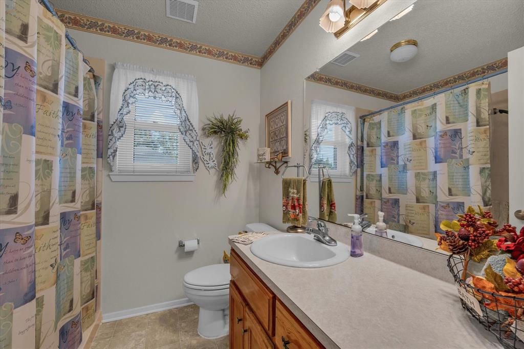 107 Fort Graham Circle Waco, TX 76705 - Photo 21 of 40 Full bathroom featuring a textured ceiling, vanity, a shower with shower curtain, light tile patterned floors, and crown molding