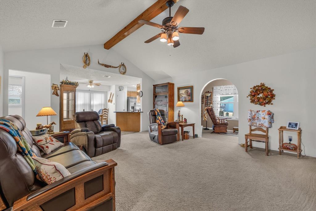 107 Fort Graham Circle Waco, TX 76705 - Photo 6 of 40 Carpeted living room featuring beamed ceiling, ceiling fan, and high vaulted ceiling