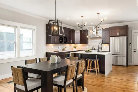 a kitchen with stainless steel appliances a dining table chairs and wooden floor