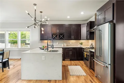 a kitchen with stainless steel appliances granite countertop a refrigerator a sink dishwasher a stove and white countertops with wooden floor