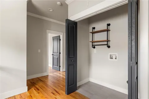 a view of a hallway with wooden floor and a bathroom