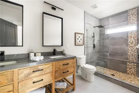 a bathroom with a granite countertop sink a mirror a toilet and shower