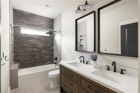 a bathroom with a double vanity sink toilet mirror and bathtub