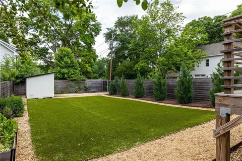 a backyard of a house with lots of plants and large tree