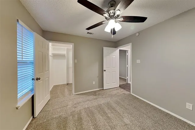 an empty room with chandelier fan and windows