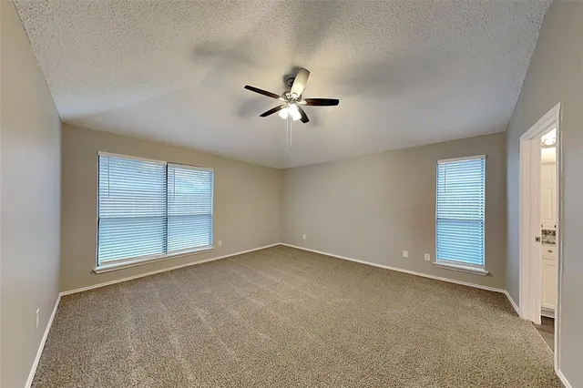 an empty room with chandelier fan and windows