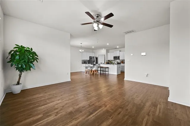 a view of a livingroom with a kitchen island a hardwood floor and a ceiling fan