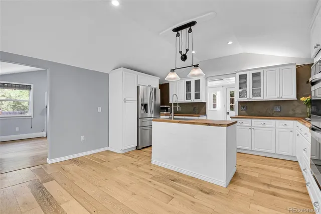 a kitchen with stainless steel appliances a stove top oven a sink a refrigerator and cabinets