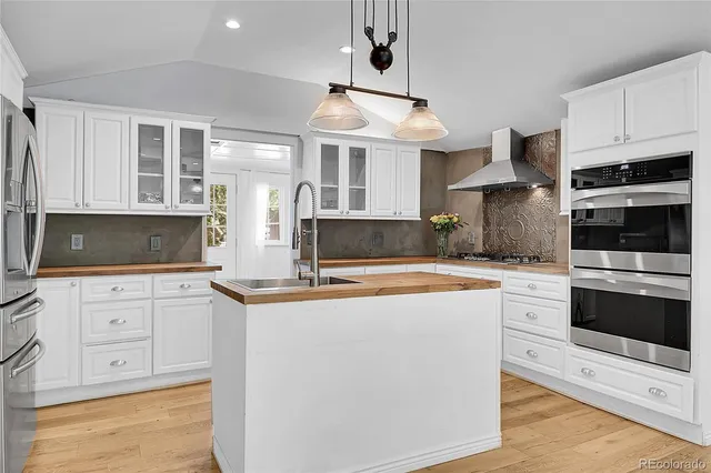 a kitchen with stainless steel appliances granite countertop a stove top oven a sink a counter space and cabinets