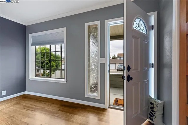 a view of an empty room with a window and wooden floor