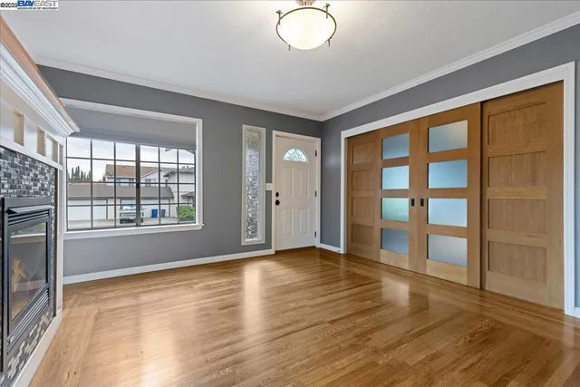 a view of an empty room with wooden floor and a window