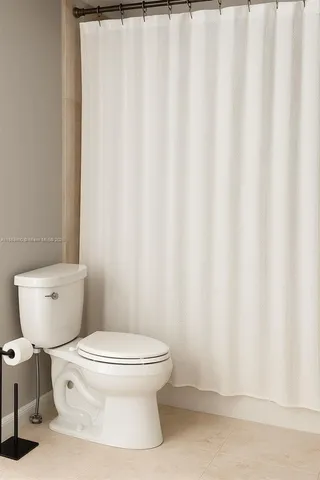 a white toilet sitting next to a white curtain