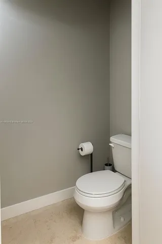 a white toilet sitting next to a white wall