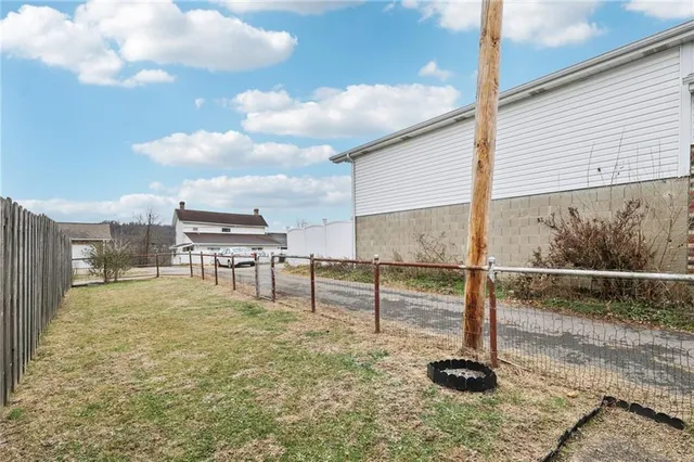 a view of a house with a small yard and wooden fence