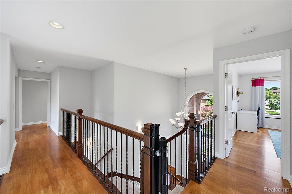 1422 Galena Rochester, MI 48306 - Photo 39 of 73 Upper-level hallway featuring wood-finish flooring, a wrought iron and wood banister, recessed lighting, an arched window, and a chandelier