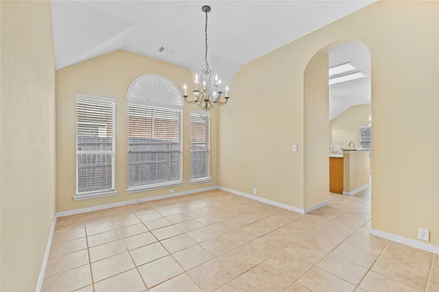 an empty room with chandelier fan and windows