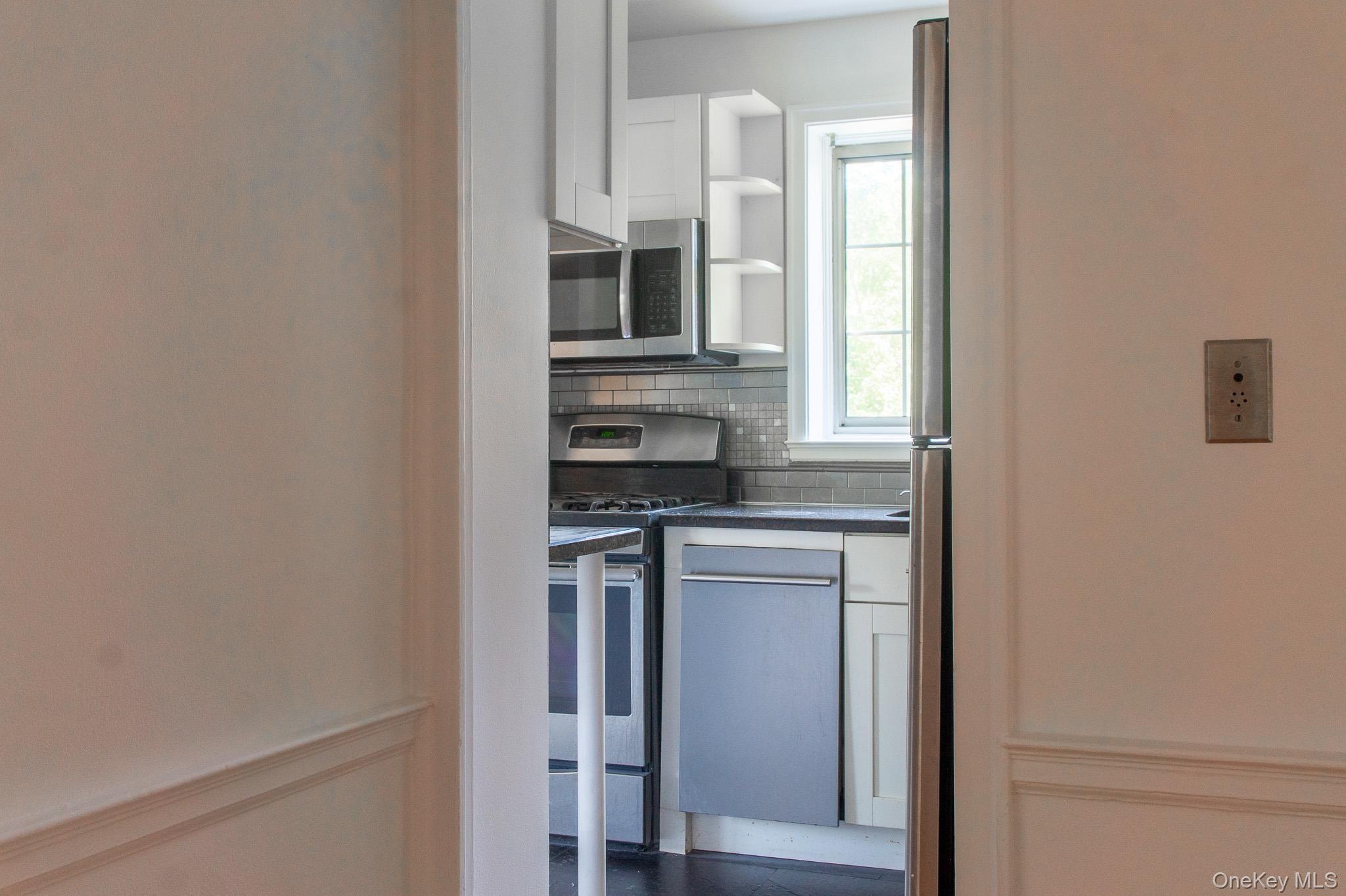 7 Chateaux Circle, Unit 7E Scarsdale, NY 10583 - Photo 8 of 28 Kitchen featuring white cabinetry, appliances with stainless steel finishes, open shelves, and tasteful backsplash