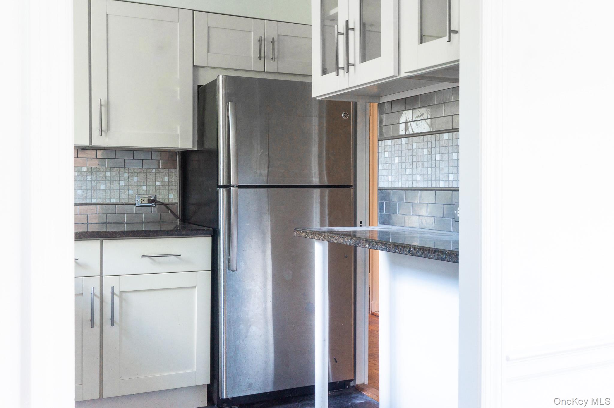 7 Chateaux Circle, Unit 7E Scarsdale, NY 10583 - Photo 10 of 28 Kitchen featuring decorative backsplash, freestanding refrigerator, glass insert cabinets, and white cabinets