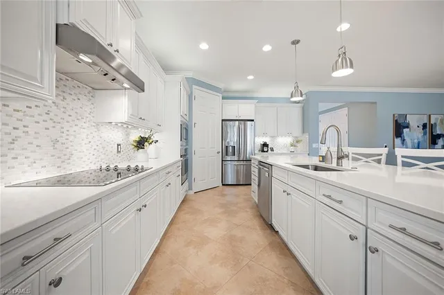 a large white kitchen with center island and stainless steel appliances