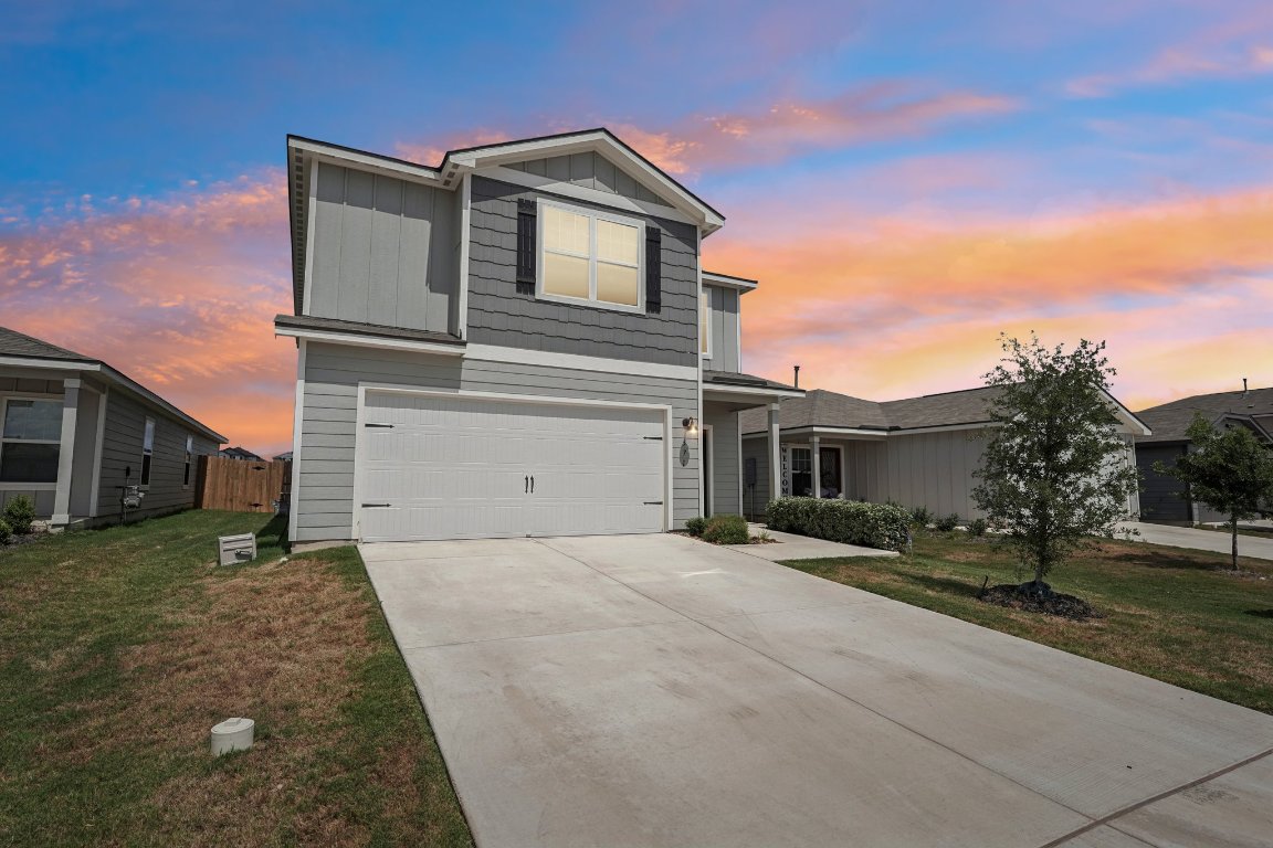Traditional-style home featuring board and batten siding, an attached garage, driveway, and a yard