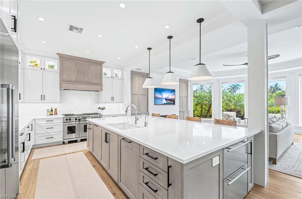 1888 6th Street South Naples, FL 34102 - Photo 9 of 37 a large kitchen with stainless steel appliances kitchen island a large counter tops and a view of living room