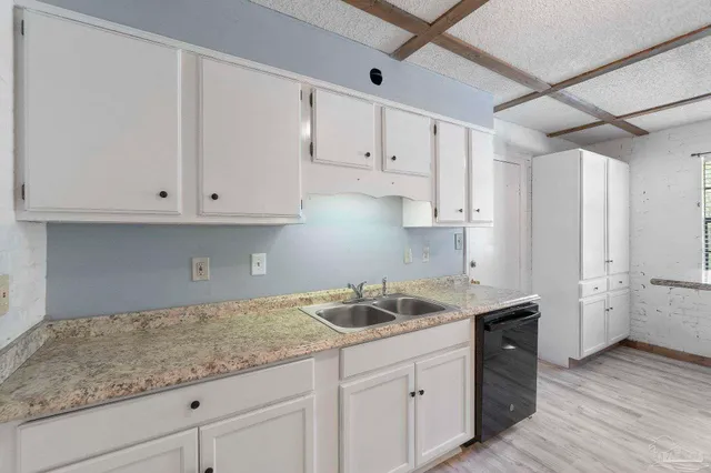 a kitchen with granite countertop white cabinets and a sink