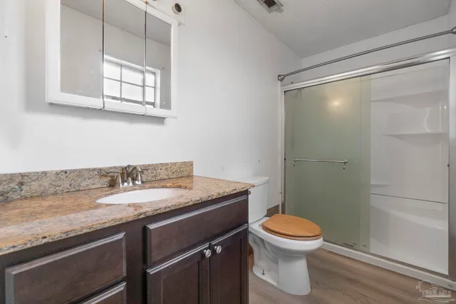 a bathroom with a granite countertop sink toilet a mirror and shower