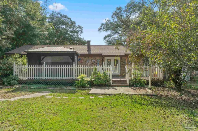 a view of a house with a small yard and a large tree