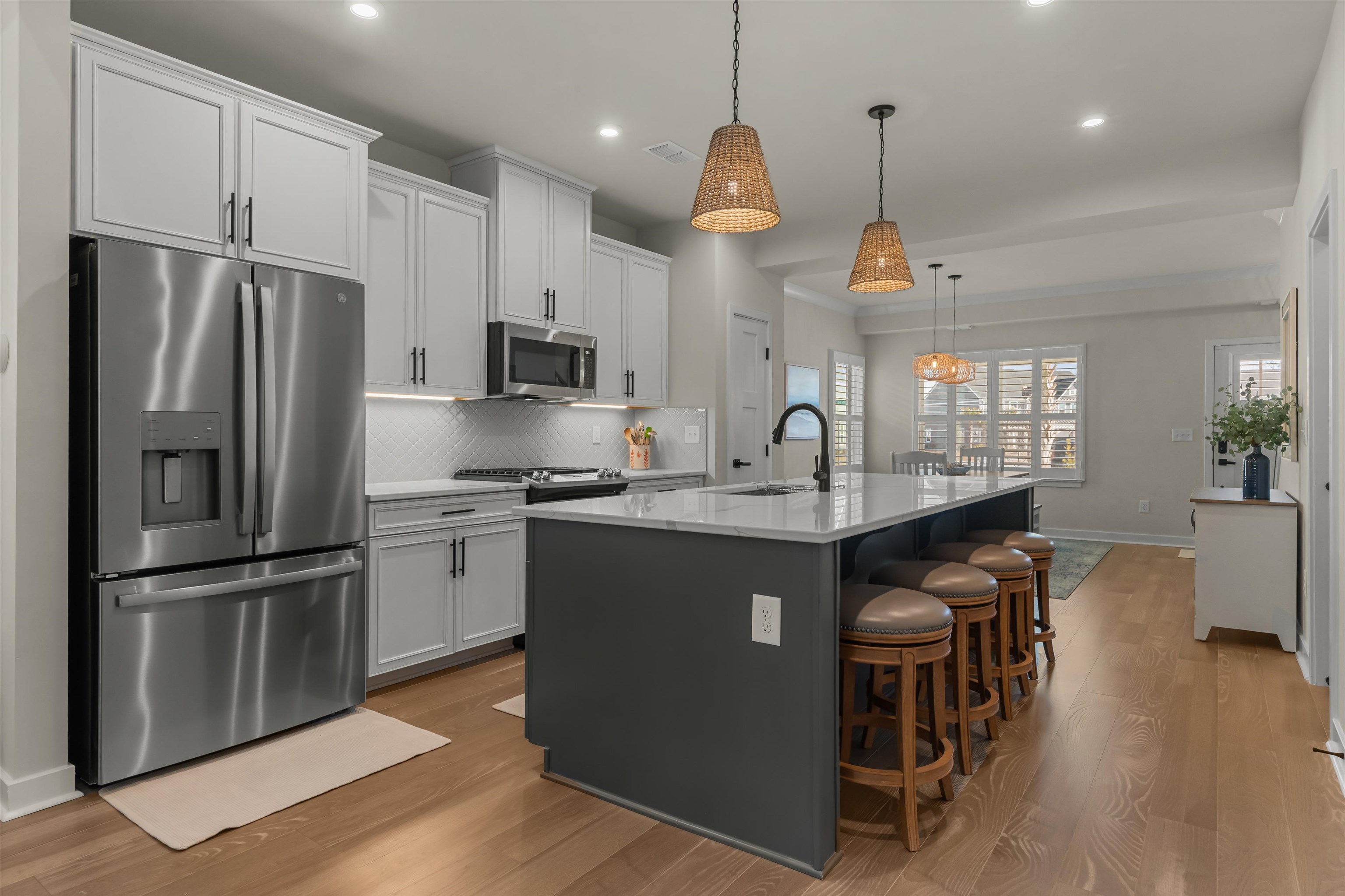 2519 Elowen Lane, Unit 9B Longs, SC 29568 - Photo 4 of 40 Kitchen featuring stainless steel appliances, a kitchen bar, dark wood-style floors, a center island with sink, and hanging light fixtures