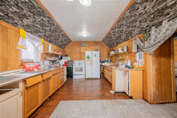 a view of a storage & utility room with fridge and wooden floor