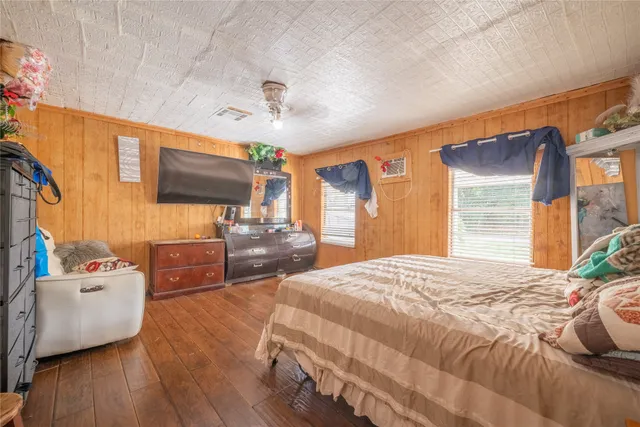 a bedroom with furniture large window and wooden floor