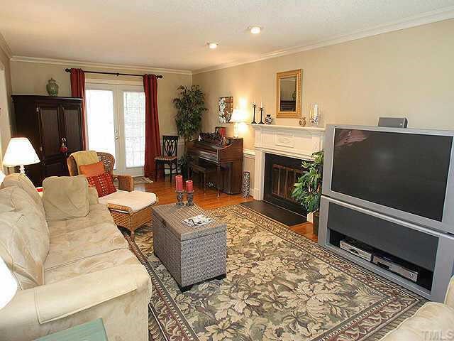 6916 Sandringham Drive Raleigh, NC 27613 - Photo 2 of 8 a living room with furniture a fireplace and a flat screen tv