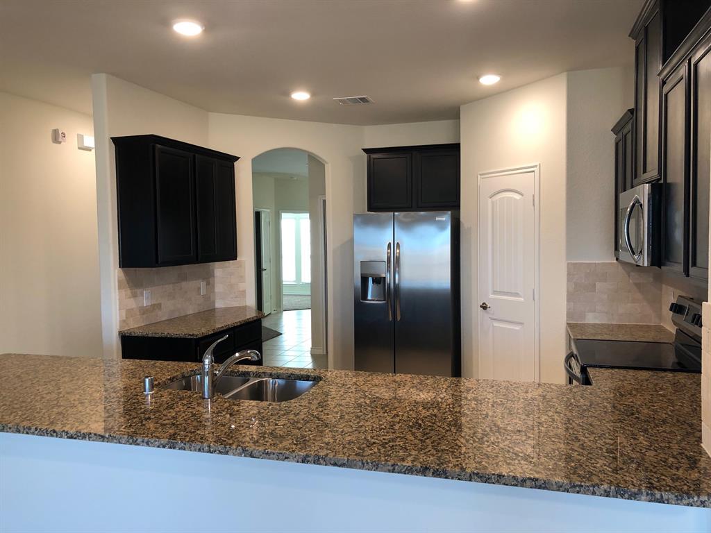 1732 Beasley Street Van Alstyne, TX 75495 - Photo 12 of 17 a kitchen with stainless steel appliances granite countertop a refrigerator and a sink