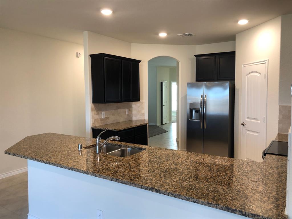 1732 Beasley Street Van Alstyne, TX 75495 - Photo 13 of 17 a kitchen with stainless steel appliances granite countertop a refrigerator a stove and a sink with wooden floor
