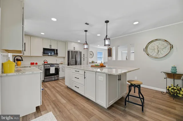 a kitchen with stainless steel appliances kitchen island granite countertop a table chairs in it and a wooden floors