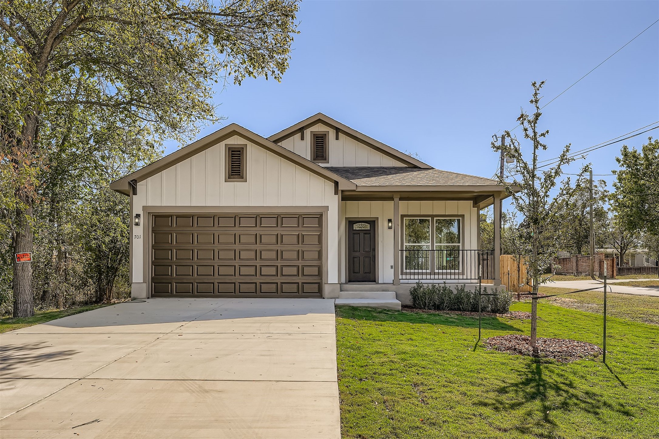 701 East 3rd Street Elgin, TX 78621 - Photo 2 of 35 View of front of property with covered porch, and batten siding, a shingled roof, concrete driveway, and a front lawn