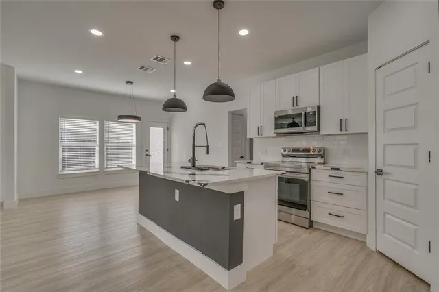 a kitchen with stainless steel appliances granite countertop a sink a stove and a wooden floors